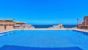 Ein klares, blaues Schwimmbecken mit Blick auf den Ozean, umgeben von Gebäuden.