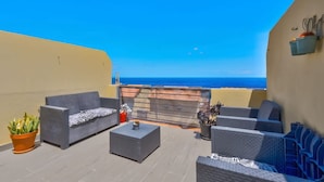 Ein Balkon mit Gartenmöbeln und Blick auf das Meer, sowie eine Gebäudefassade.