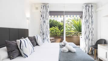 Een hotelkamer met een bed, een tafeltje, een stoel en een balkon met gordijnen.