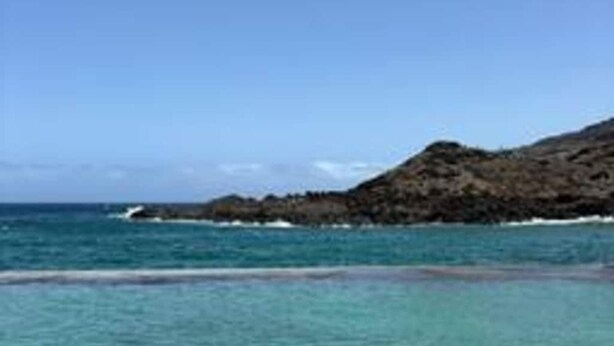 A coastal landscape with clear water and a rocky hill in the background. - Coral Sunset View in Tacoronte (Tacoronte)