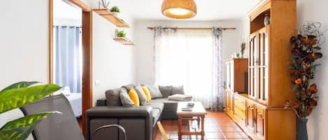 A living room with a sofa, chairs, a coffee table, a cabinet, and a hanging light fixture.