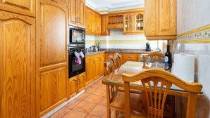 A kitchen with wooden cabinets, a glass table, and a stove. - Apartamento Terraza Los Realejos (Los Realejos)