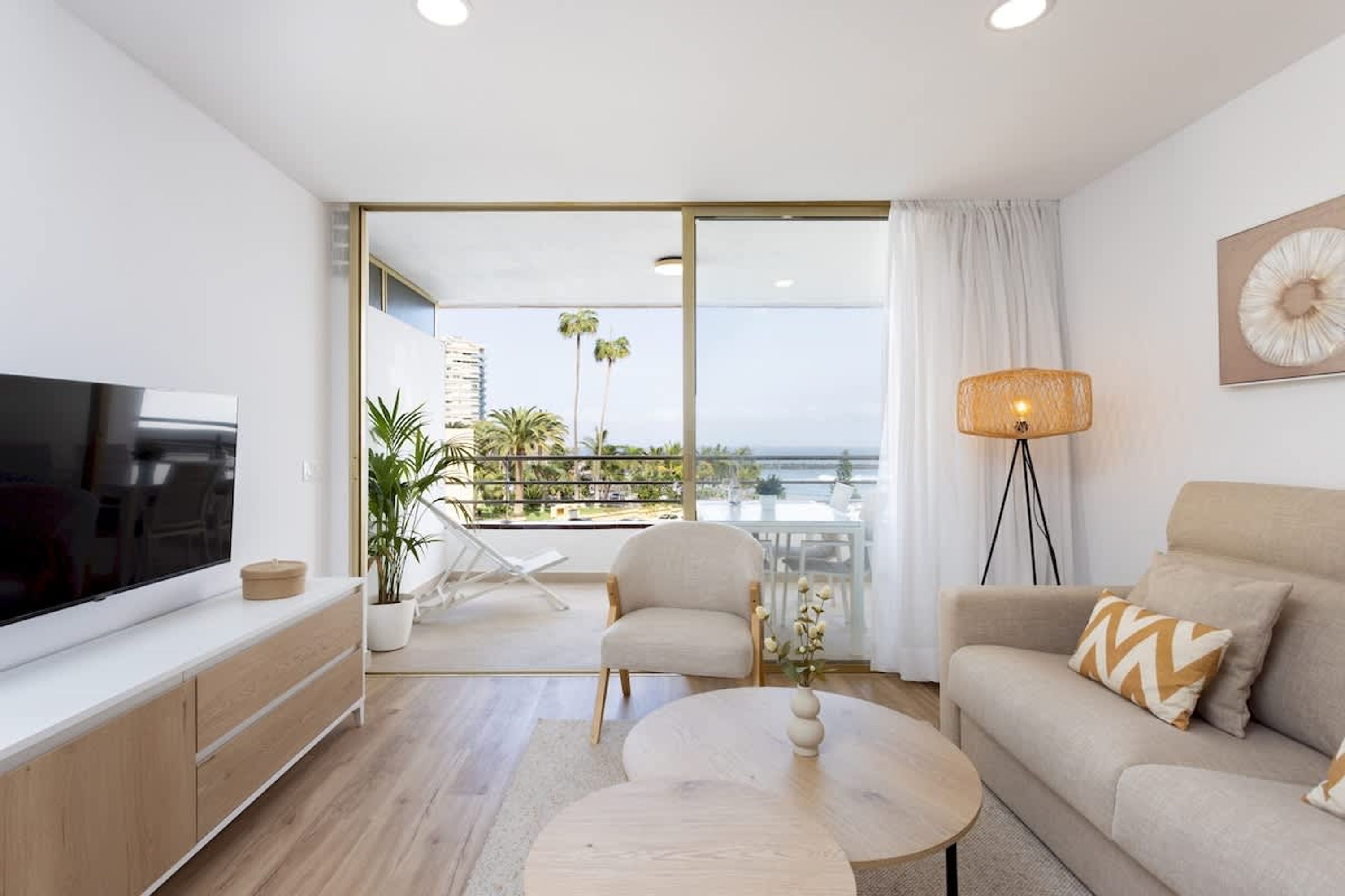A modern living room with a flat-screen TV, a sofa, a coffee table, and a floor lamp.