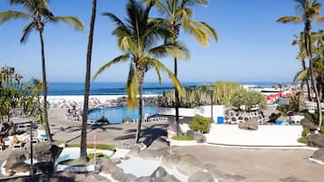 Een resort met een zwembad, palmbomen en uitzicht op de oceaan.