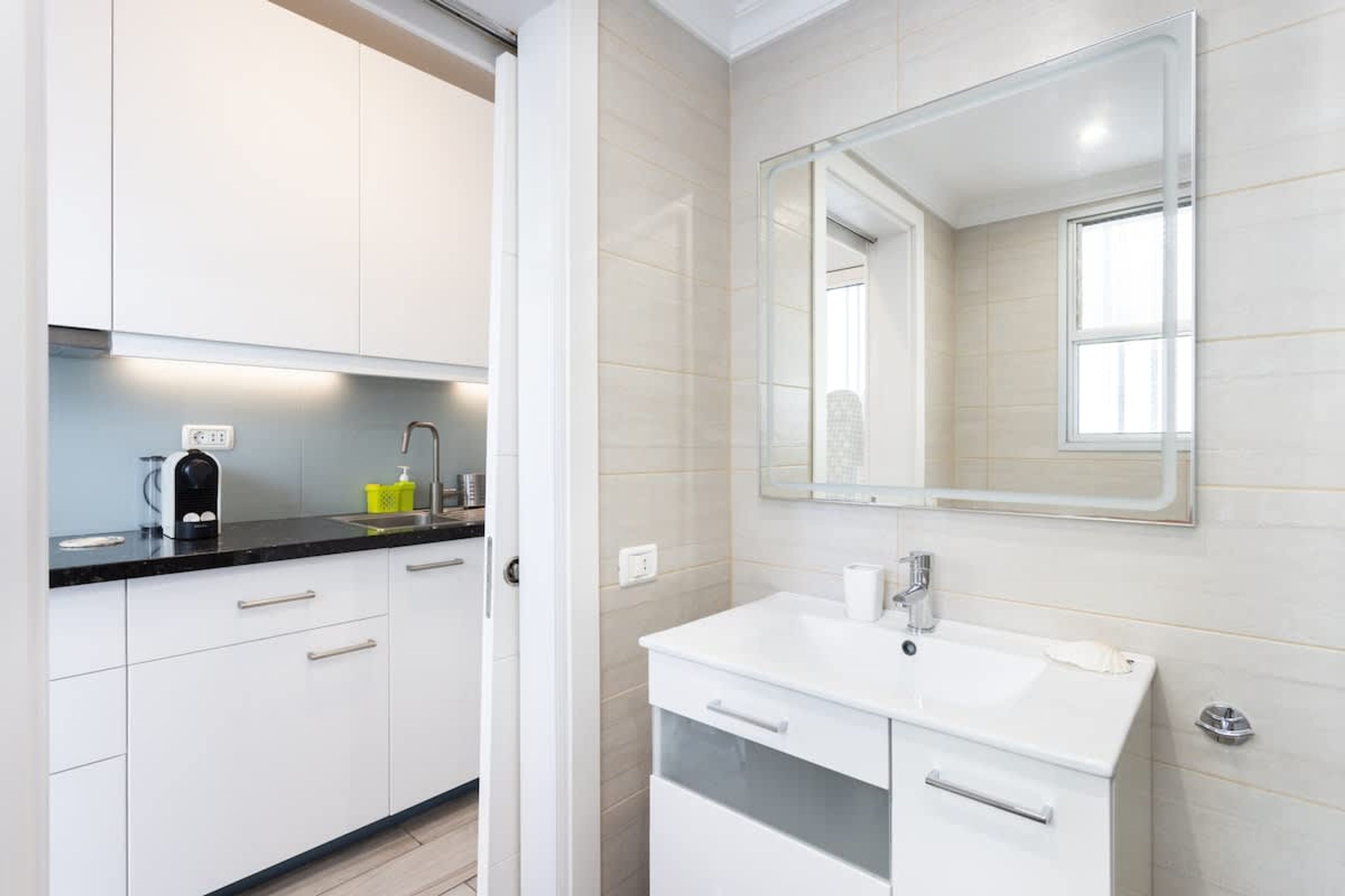 Een moderne badkamer met een wit wastafelmeubel, spiegel en kastjes.
