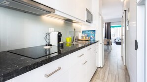 Een moderne keuken met witte kasten, een zwart aanrecht en een magnetron.
