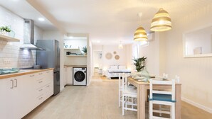 Eine moderne Küche mit integriertem Waschmaschine, ein Essbereich mit Holztisch und Stühlen sowie Pendelleuchten.