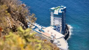 A coastal hotel with a prominent tower, a flat-roofed building, and a view of the sea. - Apartamento Zoraida del mar (Tacoronte)