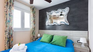 A bedroom with a bed, two pillows, a mirror, a window, and curtains. - Apartamento Zoraida del mar (Tacoronte)