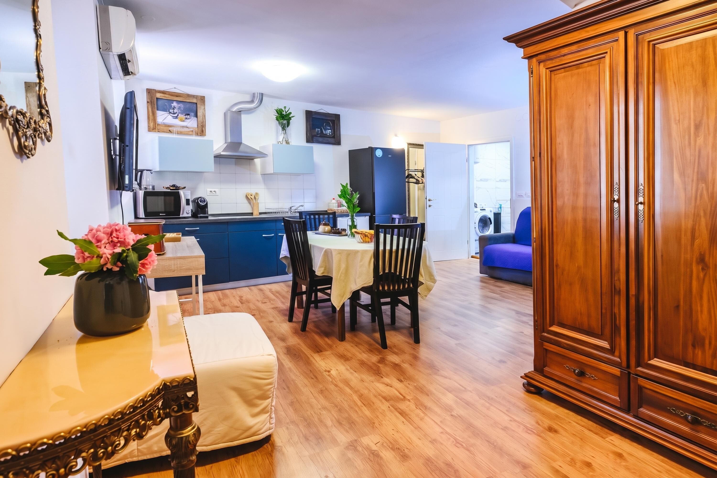 A modern kitchen with a dining area, wooden cabinets, and a blue countertop.