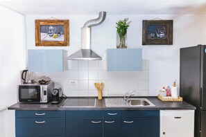 A kitchen with a microwave, toaster, sink, cabinet, and a stainless steel range hood. - Nobile Studio in the Historic Town (Koper)