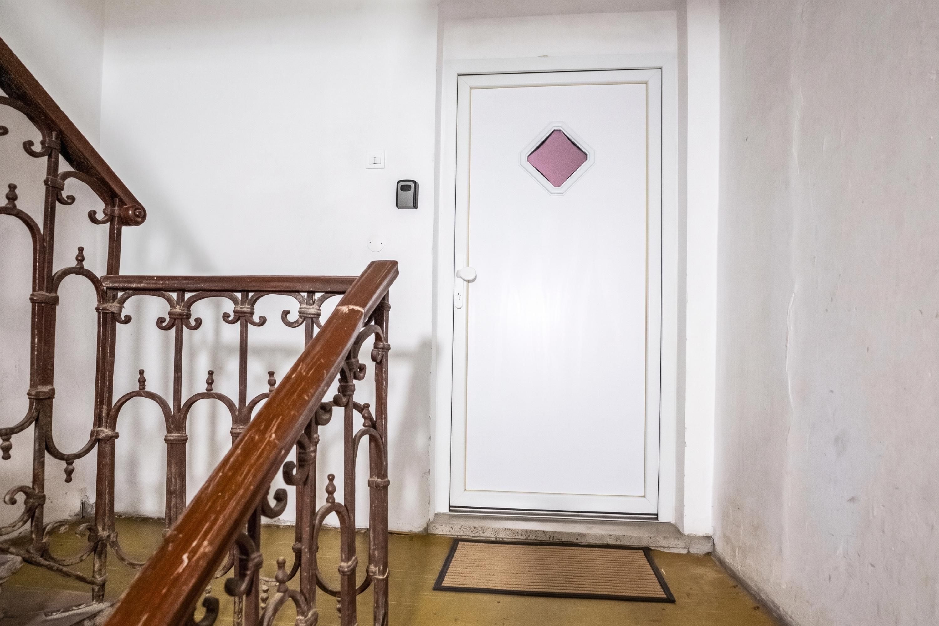 A staircase with ornate metal railings leading to a white door with a small diamond-shaped window.