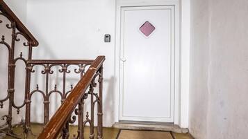 A staircase with ornate metal railings leading to a white door with a small diamond-shaped window.