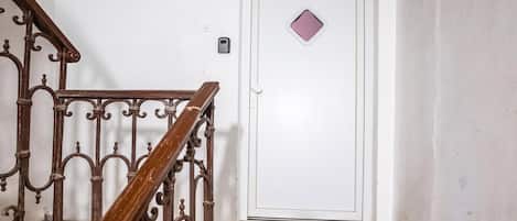 A staircase with ornate metal railings leading to a white door with a small diamond-shaped window.