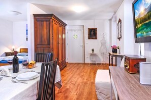 A well-lit room with a dining table set for two, a wooden wardrobe, a white door with a keyhole, and a painting on the wall. - Nobile Studio in the Historic Town (Koper)