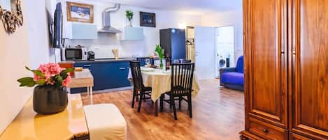A dining area with a table set for two, a cabinet, and a kitchen in the background.