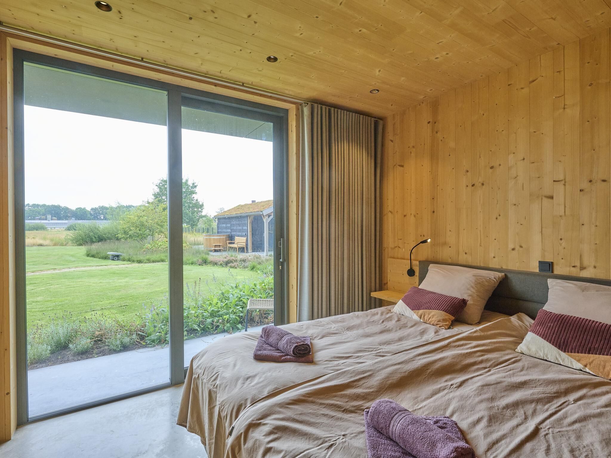 A bedroom with a large sliding glass door leading to a grassy outdoor area.