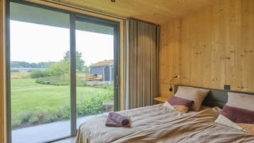 A bedroom with a large sliding glass door leading to a grassy outdoor area.