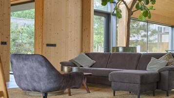 A modern living room with a grey sofa, a matching armchair, and a large window with a view of trees.