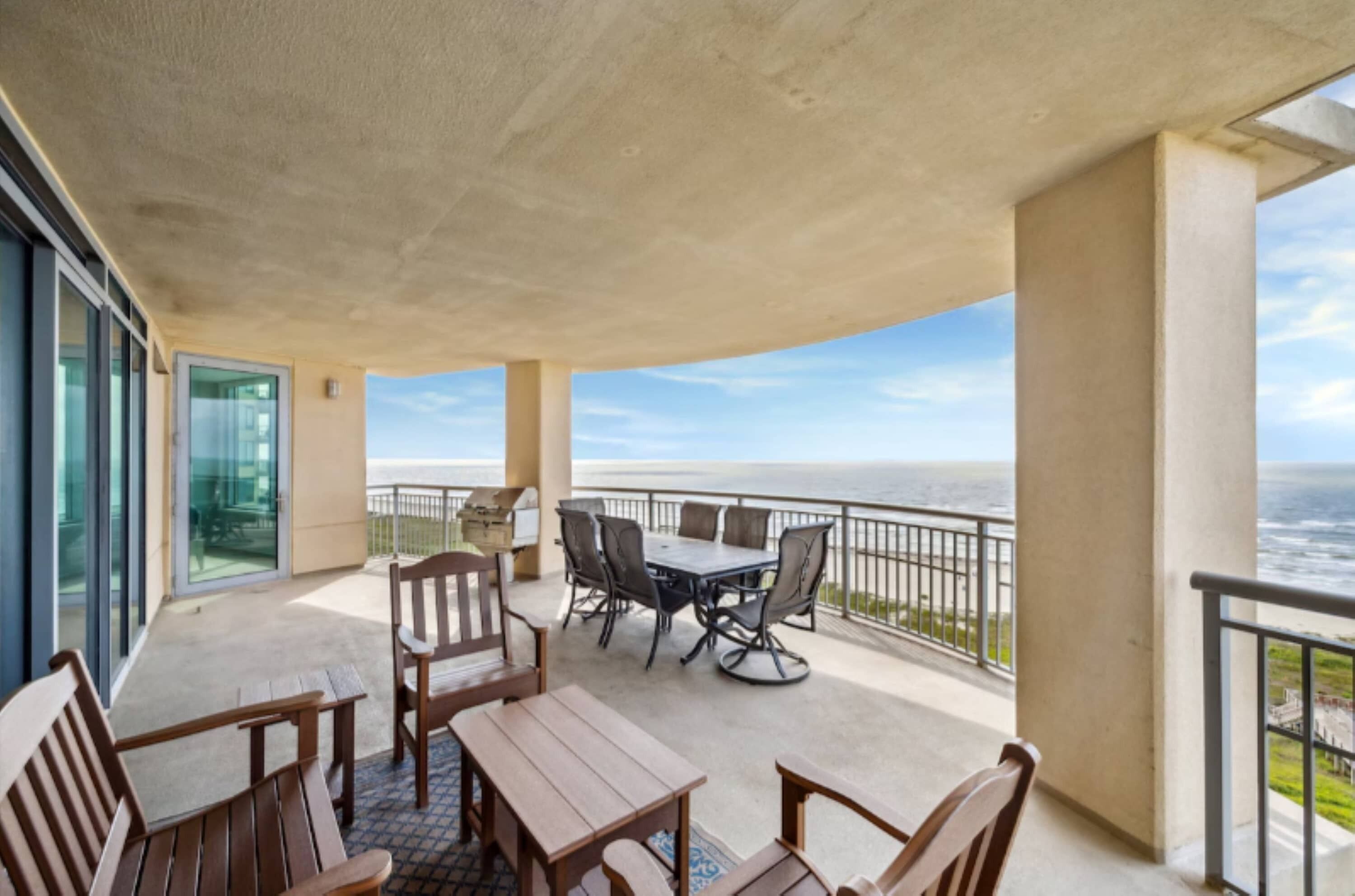 A balcony with a table and chairs, a glass door, and a view of the ocean.