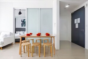 Ein modernes Zimmer mit Esstisch, Stühlen, einer Couch und einem Bett.