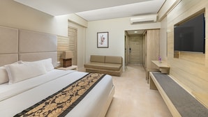 A hotel room with a large bed, a sofa, a TV, and a desk.