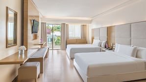A hotel room with two beds, a desk, a TV, and a balcony with curtains.