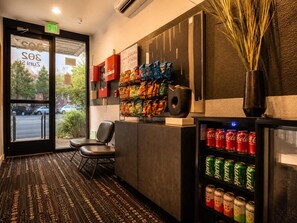 Ein Hotel-Empfangsbereich mit Sitzgelegenheiten, einer Snackwand und einem Getränkekühlschrank.