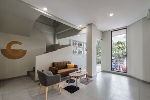 A modern interior with a staircase, a sofa, a chair, and a coffee table. - Cove Atman (Jakarta)