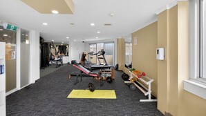 Un gimnasio con equipo de ejercicio, una colchoneta amarilla y una ventana.
