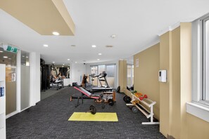 Ein Fitnessraum mit Trainingsgeräten, einer gelben Matte und einem Fenster.
