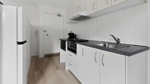 Una cocina moderna con armarios blancos, encimera negra y pileta de acero inoxidable.