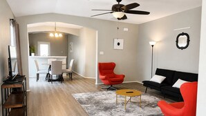 A modern living room with a black sofa, red armchair, and a dining area with a white table and chairs. - 3-bedroom house in peaceful Houston with cool AC breeze (Houston)