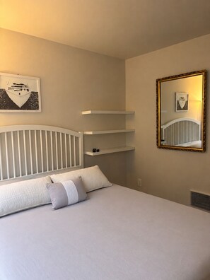 A bedroom with a bed, pillows, a headboard, a bedside table, a mirror, and wall-mounted shelves. - 3 Bedroom Townhouse with Outdoor Rooftop Deck (Seattle)