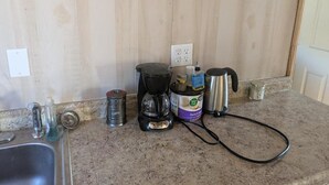 Ett kök med en kaffebryggare, en vattenkokare, en kaffekvarn och en behållare.