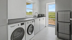 Une cuisine moderne équipée d’un lave-linge, d’un four à micro-ondes et offrant une vue sur un champ par la fenêtre.