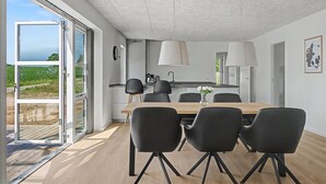Une cuisine moderne avec un coin repas, de grandes fenêtres et une vue sur l’extérieur.