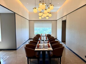 A conference room with a long table, brown chairs, and a modern chandelier. - J J Plaza JHV Cantonment Varanasi (Varanasi)