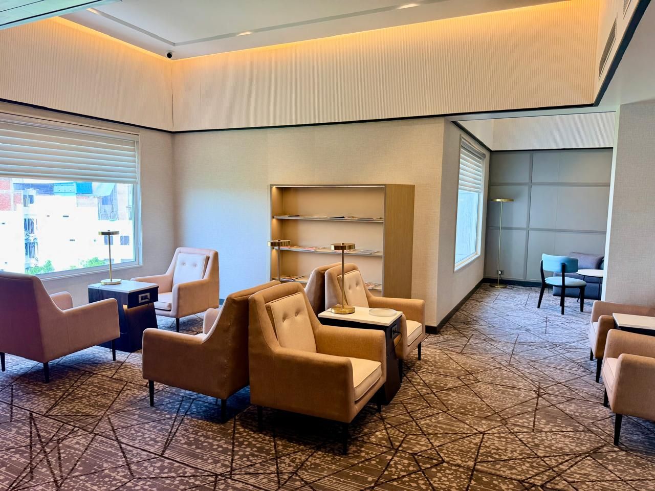 A hotel lobby with seating areas, a reception desk, and a bookshelf.