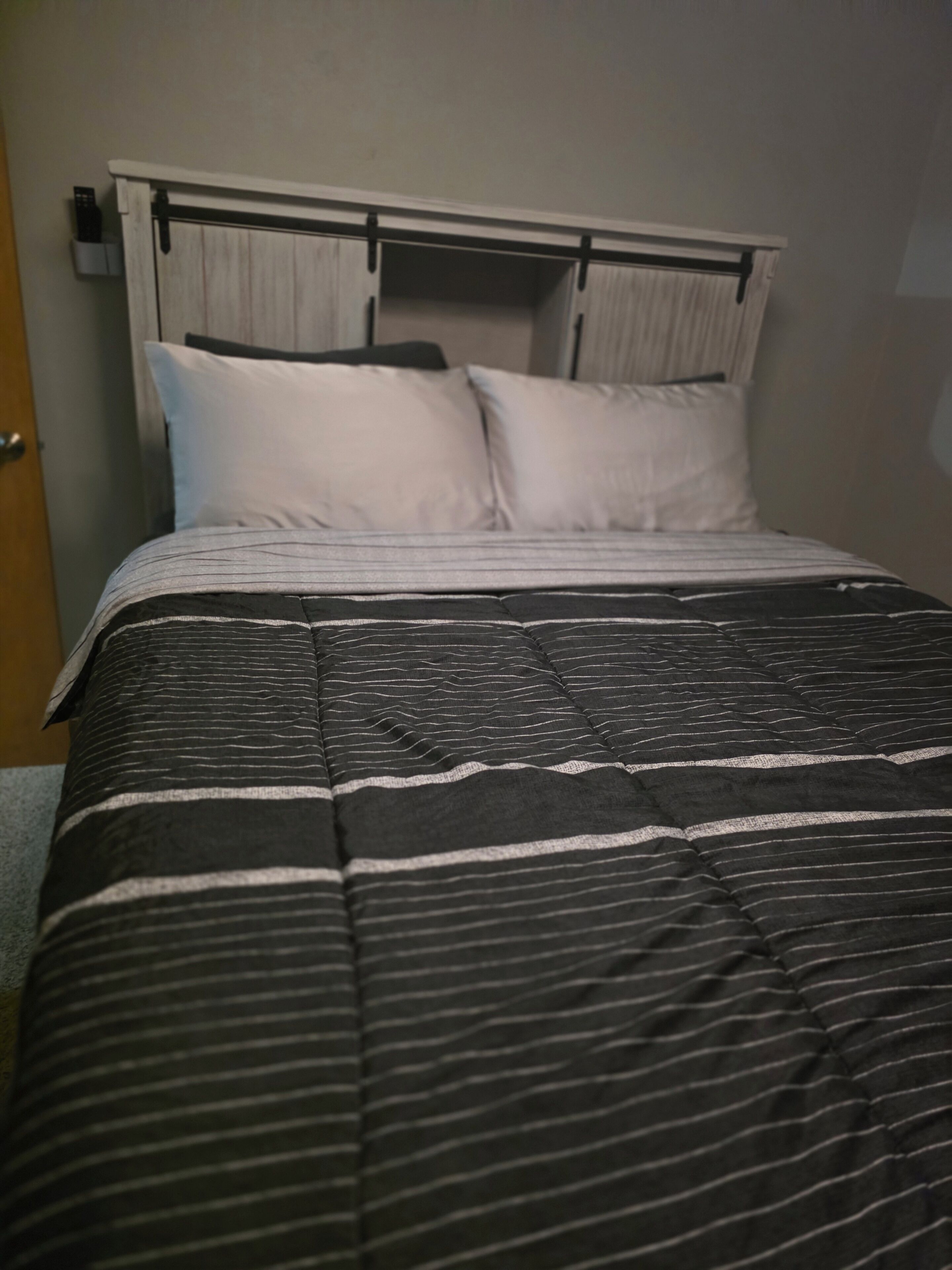 A bed with a striped bedspread and two pillows.