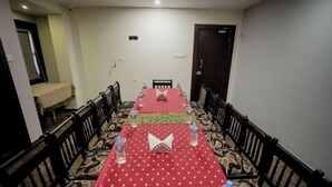 A dining area with a table set for four, surrounded by chairs, and a bed in the background.