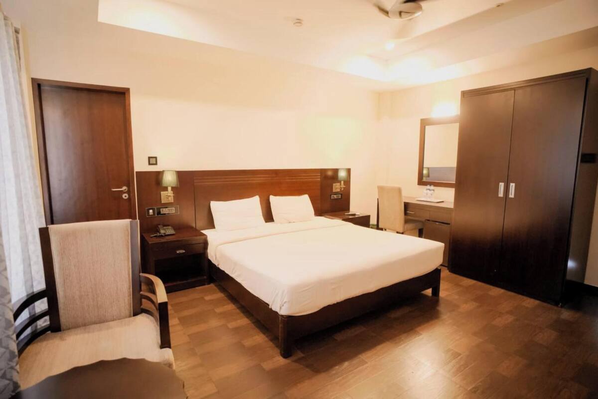 Een hotelkamer met een houten bed, een stoel, een bureau, een kledingkast en een spiegel.