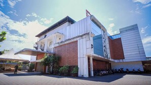 A modern building with a flat roof, a balcony, and a parking area with motorcycles.