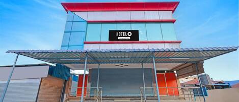 A hotel entrance with a sign, steps, and a covered area.
