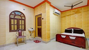 A bedroom with a bed, a chair, a sink, and a window.