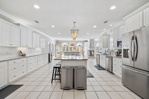A spacious kitchen with white cabinetry, stainless steel appliances, and a central island.