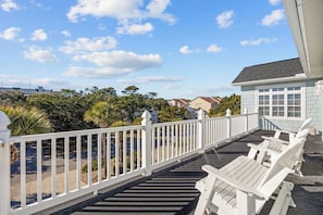 A balcony with white railings and chairs, overlooking a residential area with houses and trees.