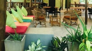 A covered outdoor seating area with wicker furniture and potted plants.