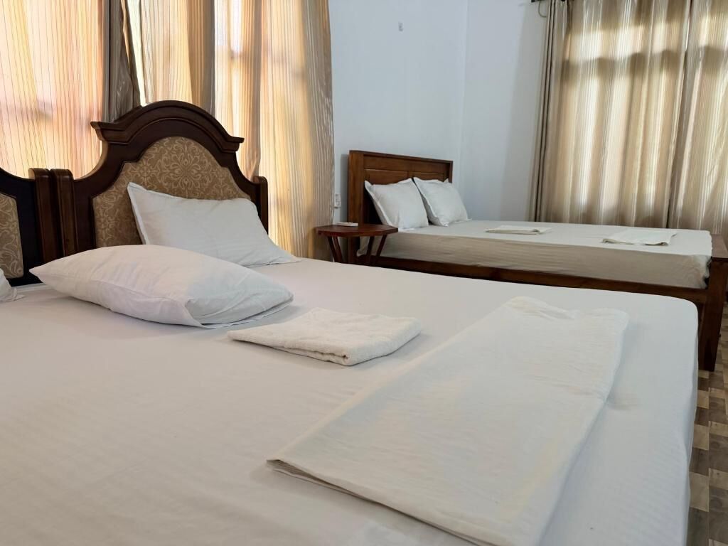 A hotel room with two beds, a wooden headboard, and a small bedside table.