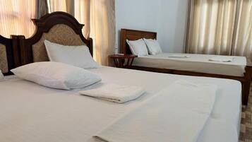 A hotel room with two beds, a wooden headboard, and a small bedside table.